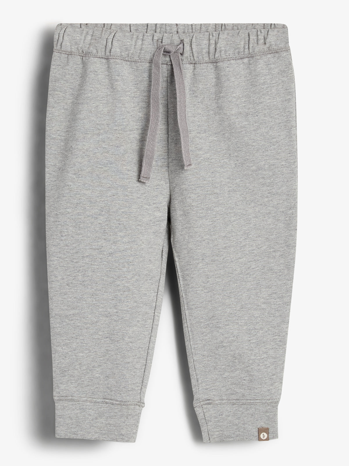 Gray sweatpants with a drawstring waistband hang neatly against a white background, featuring a small brown tag at the bottom left cuff.