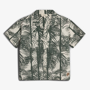 Short-sleeved shirt features a tropical palm leaf print in dark green on a light background. It has buttons down the front and a collar, set against a plain backdrop.