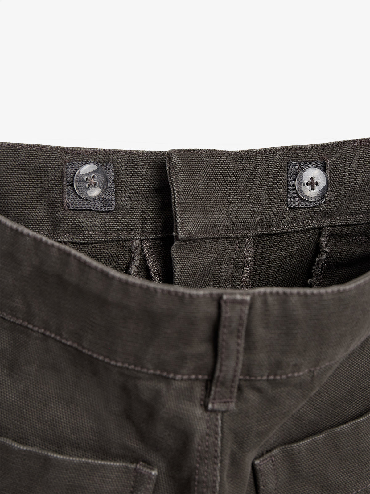 The object is a pair of brown pants with the waistband featuring two black buttons. They are laid flat against a plain, neutral background.