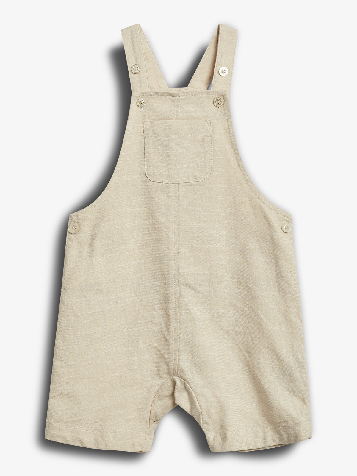 Beige children's romper with front pocket and adjustable straps featuring buttons. Set against a plain white background.
