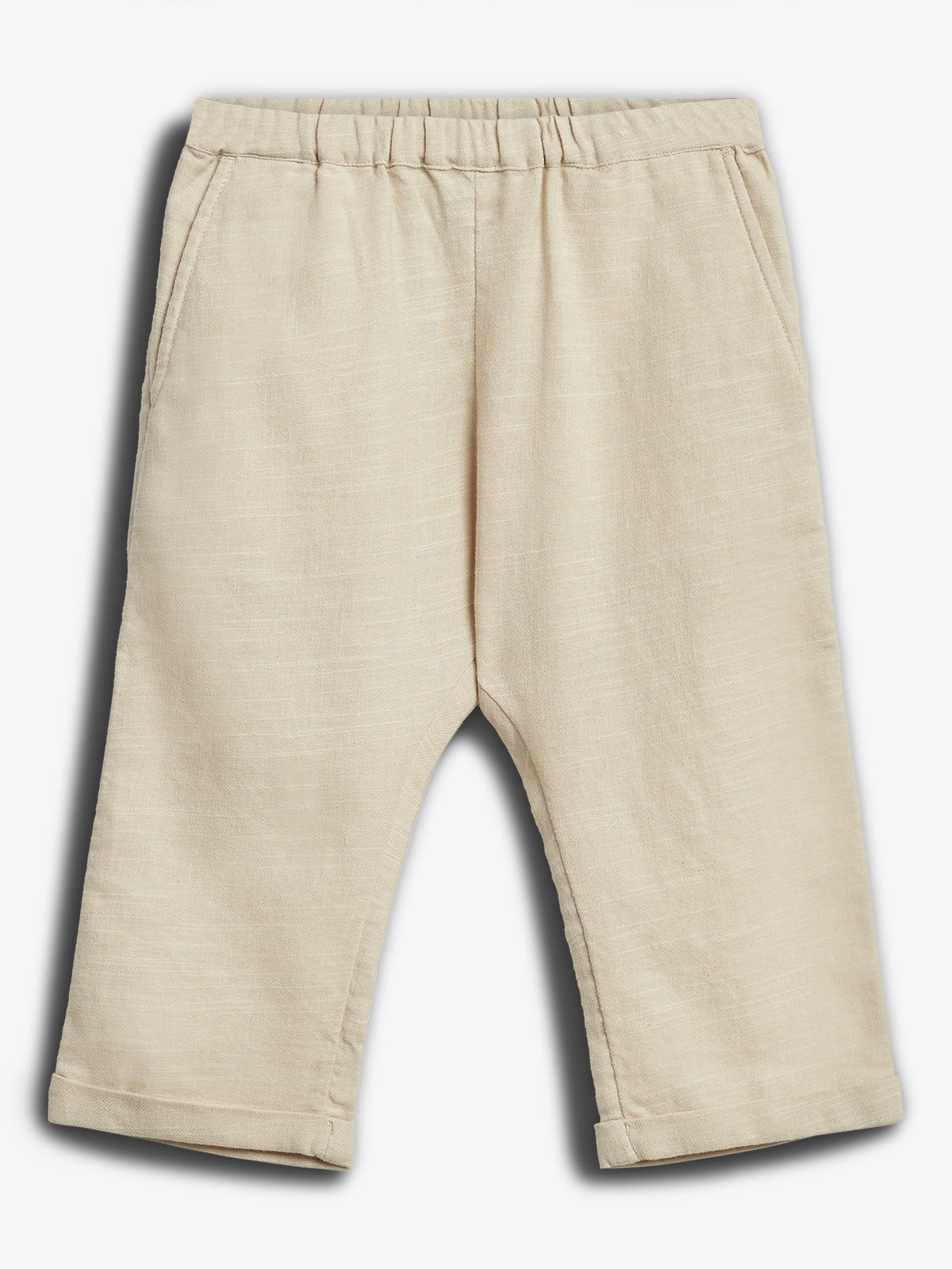 Beige linen pants lie flat, with an elastic waistband and front pockets. The turned-up cuffs add a finished touch, set against a plain white background.