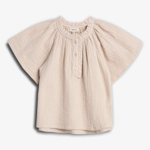 A cream-colored, short-sleeved baby blouse hangs in a white background. The blouse features a gathered neckline, button closure, and loose, textured fabric, creating a casual and comfortable look.