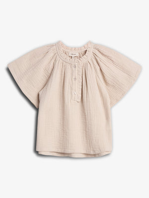 A cream-colored, short-sleeved baby blouse hangs in a white background. The blouse features a gathered neckline, button closure, and loose, textured fabric, creating a casual and comfortable look.