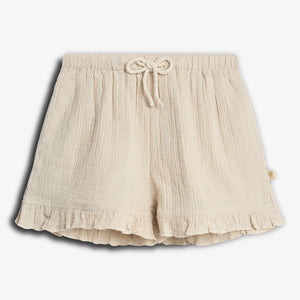 Cream-colored shorts with a drawstring waist and subtle floral pattern. The hem features ruffles, adding a decorative touch. The shorts are laid flat against a plain white background.