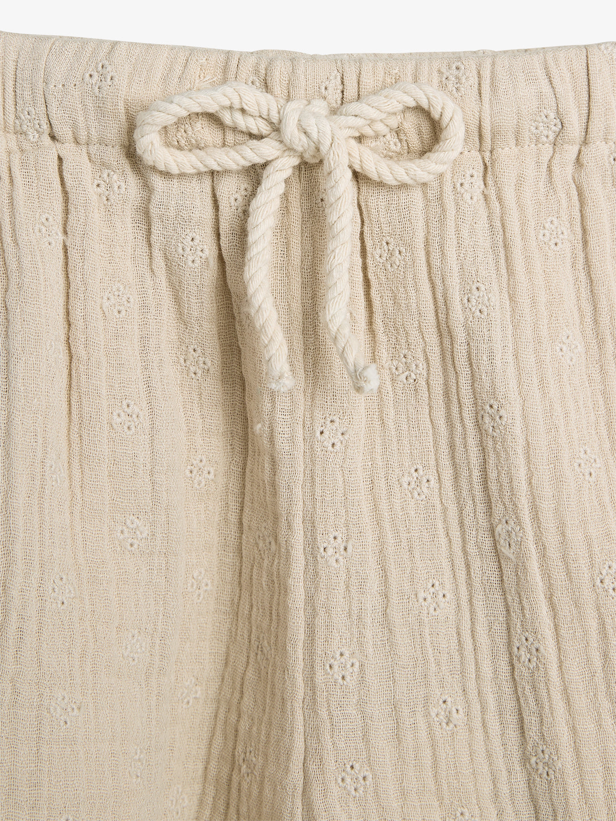 Beige fabric shorts with an adjustable rope bow tie, featuring a subtle floral texture, against a plain white background.