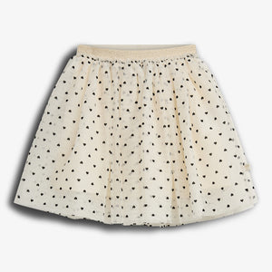 A cream-colored skirt features a pattern of small black hearts. It is pleated with a gold elastic waistband, displayed against a plain white background.