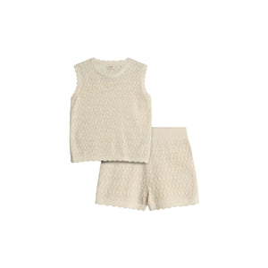 A cream-colored sleeveless knit top and shorts set lies against a plain background, showcasing a delicate diamond pattern and scalloped edges, exuding a soft and casual style.