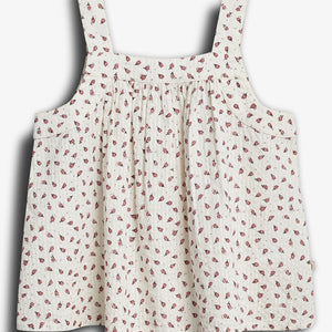 Sleeveless, floral-patterned dress with thick straps hangs against a plain backdrop. The fabric is light-colored with small, red floral designs scattered throughout.