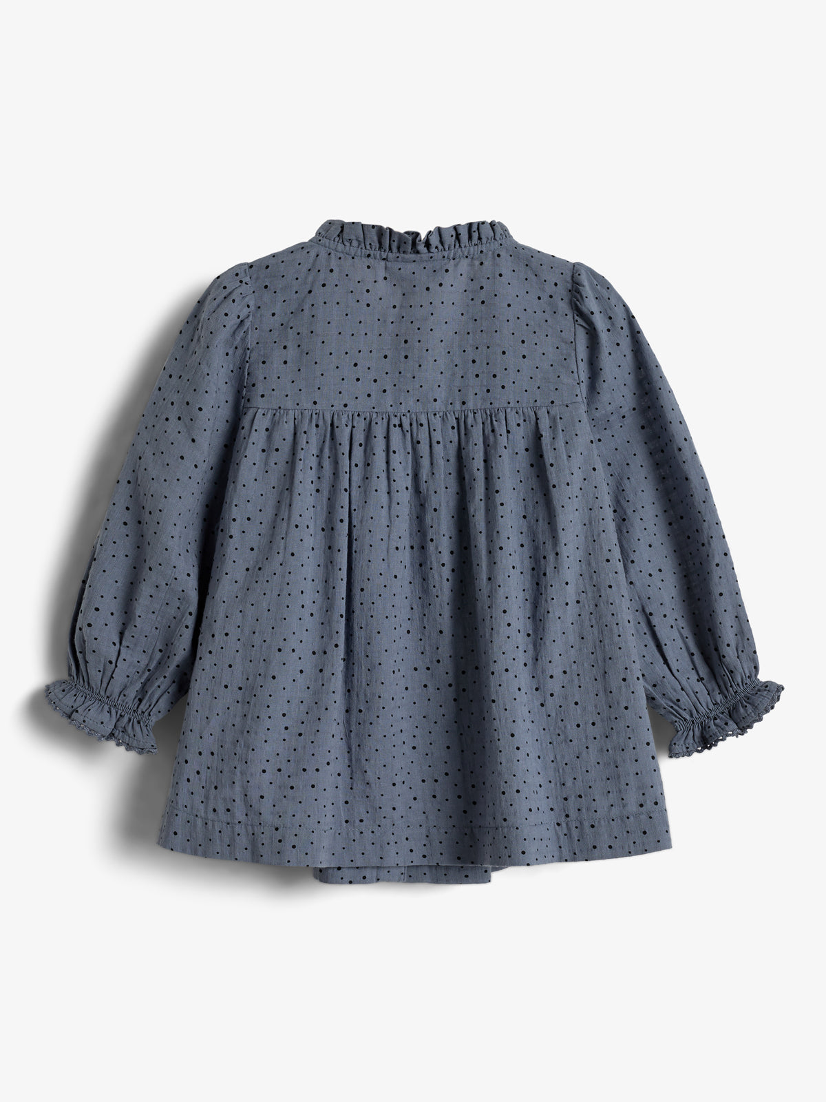 A blue blouse with black polka dots and ruffled sleeves is laid flat against a plain white background, showcasing its back design and gathered detailing.