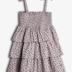 A sleeveless, lavender dress with thin shoulder straps features tiered ruffles and a small floral pattern, creating a delicate, layered appearance against a plain background.