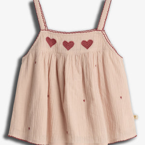 A light pink sleeveless top with red heart embroidery across the chest. It has thin straps and small scattered heart patterns, complementing a delicate, textured fabric.