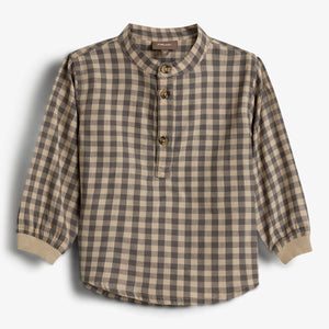 A plaid checkered shirt with long sleeves and a round collar, featuring three brown buttons on the front. The shirt is set against a plain white background.