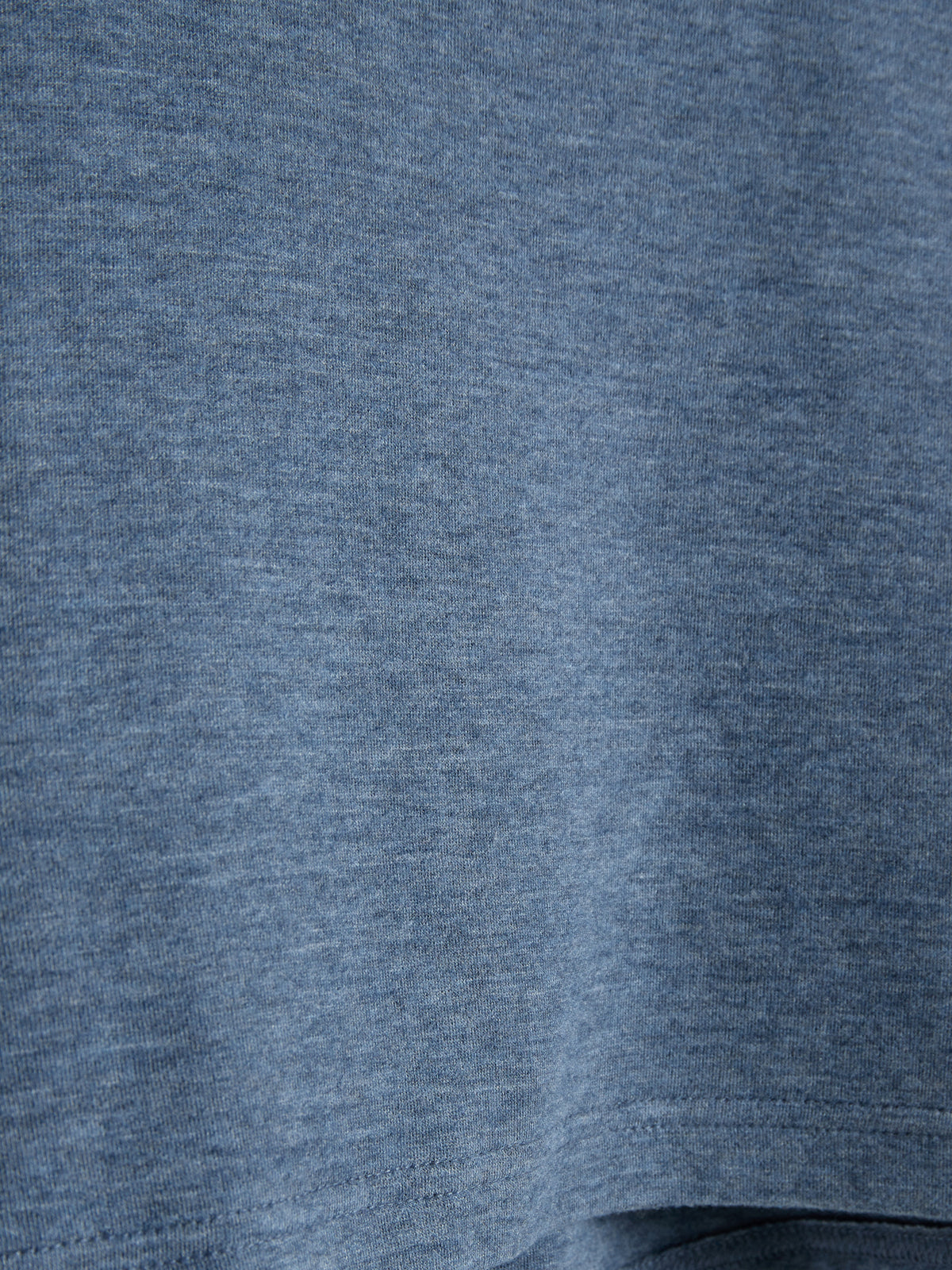 Close-up view of a blue fabric, showing a jersey knit texture. The material is slightly wrinkled, suggesting gentle movement or draping, with no visible surroundings.