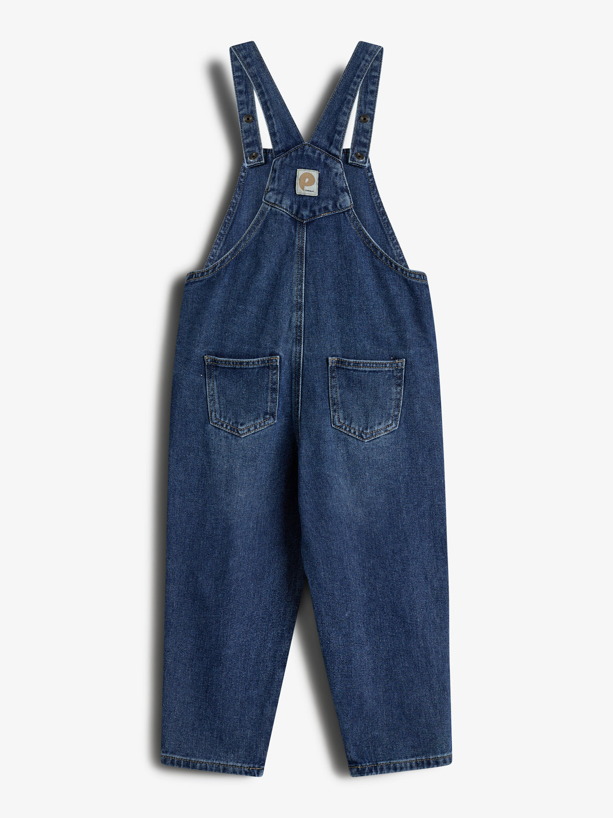 Denim overalls with adjustable shoulder straps feature two chest buttons and two front pockets, hanging on a plain white background. A small patch with a logo is centered on the chest.