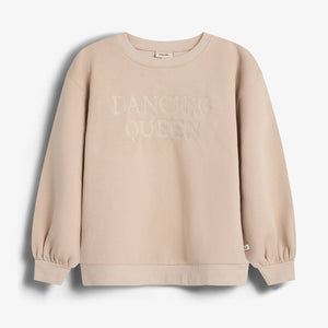Sweatshirt displays "DANCING QUEEN" text on the front. It's beige with ribbed cuffs and hem, positioned against a plain white background.