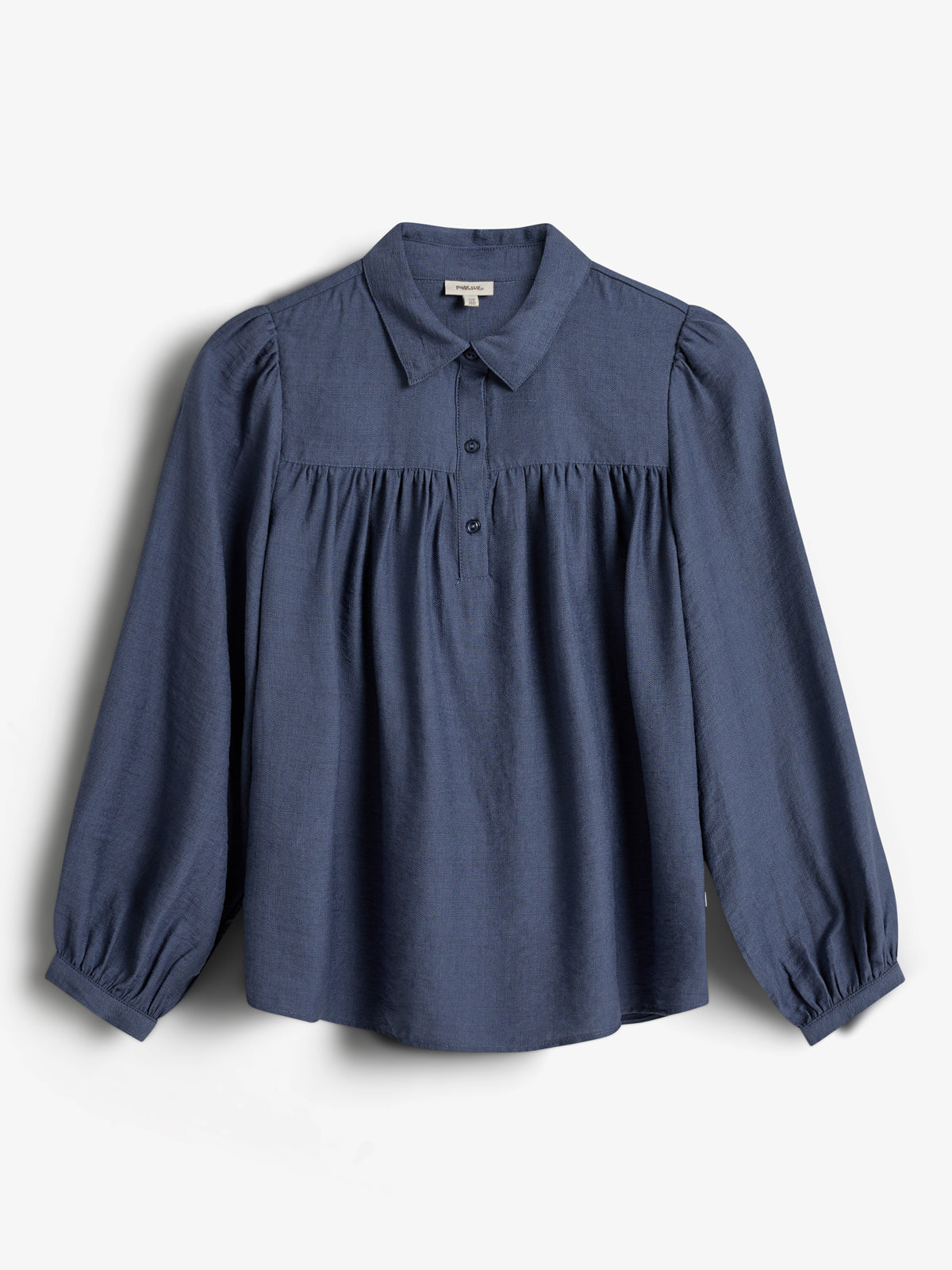 Blue long-sleeve blouse hangs against a plain white background. It features a collar, buttons down the chest, and gathered fabric near the shoulders and cuffs, creating a soft, flowing appearance.