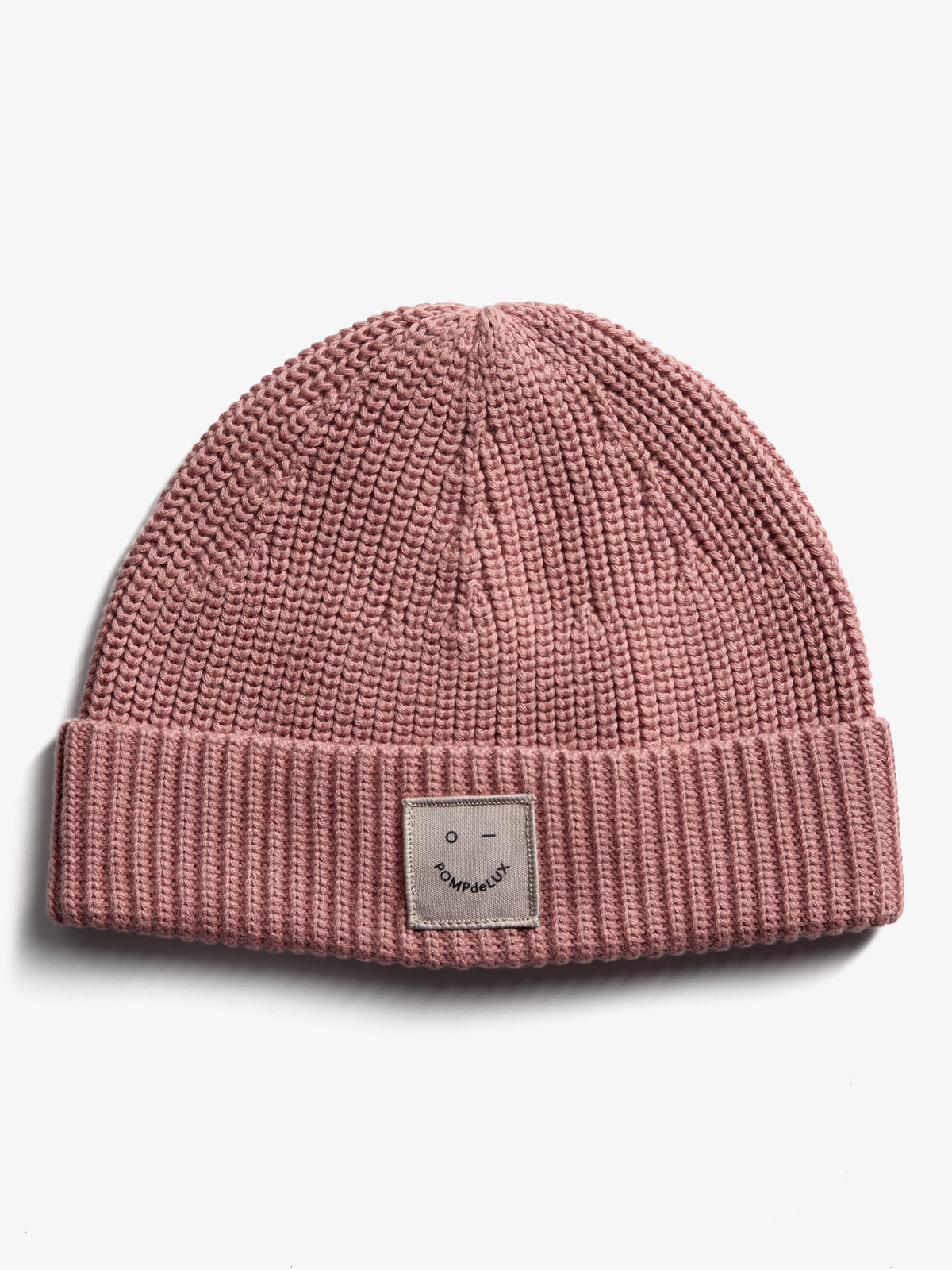 A pink knit beanie with a folded brim, featuring a patch showing a simple face and the text "POMPEDE LUX," set against a plain white background.